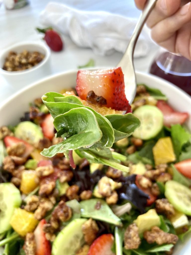 taking a bite of strawberry walnut salad